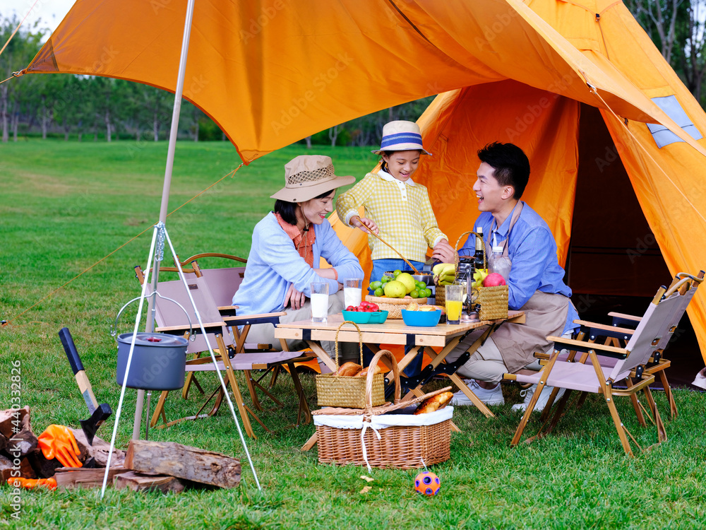 A happy family of three cooks outdoors