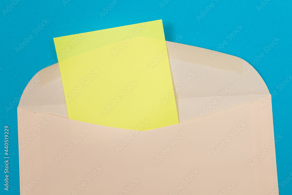 Beige Envelope with Blank Yellow Sheet of Paper Inside, Lying on Blue Background - Mock Up with Copy