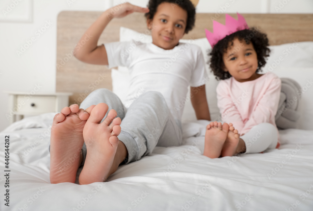 African-American children sitting on bed in room