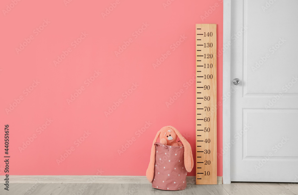 Wooden stadiometer and toy near color wall