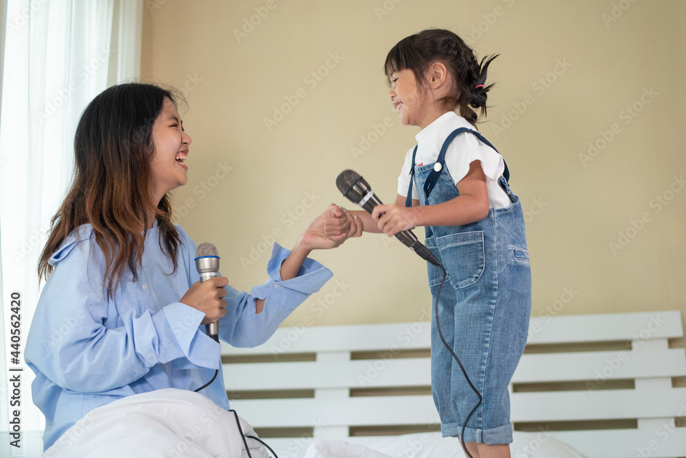 快乐的亚洲家庭爱孩子，孩子和她的妹妹拿着麦克风一起唱歌