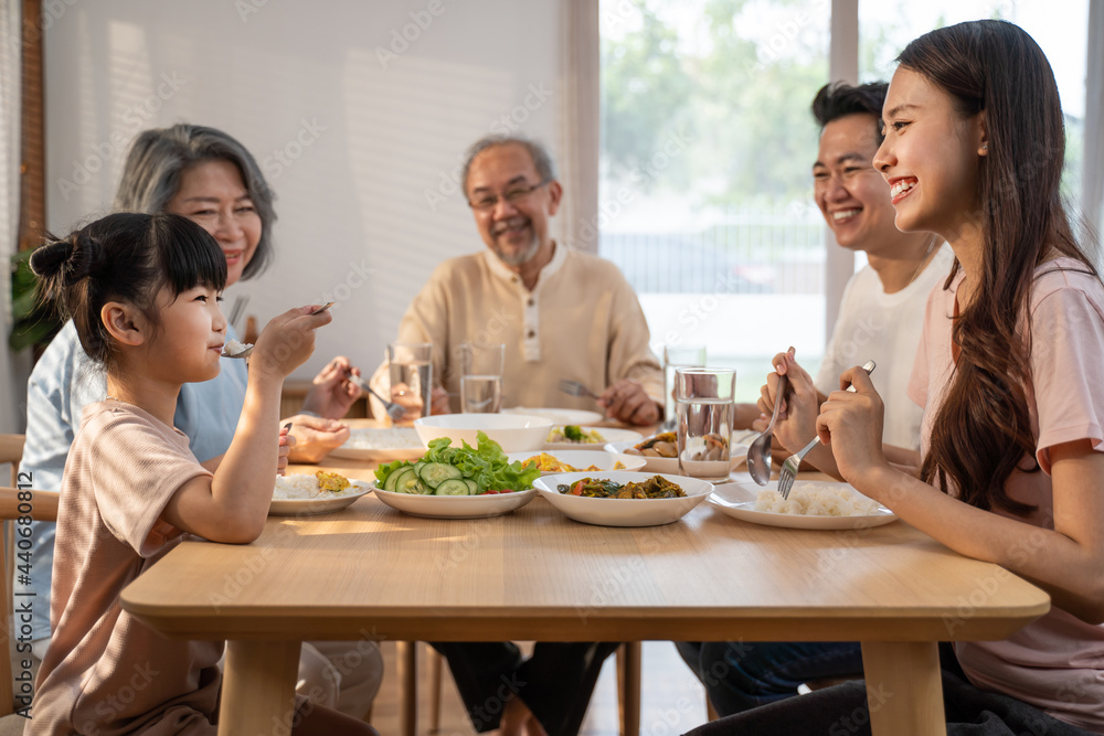 Asian big happy family eat foods on dinner table together in house.