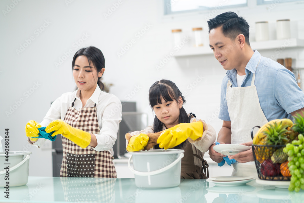 Asian happy family, parents teach young daughter clean kitchen at home