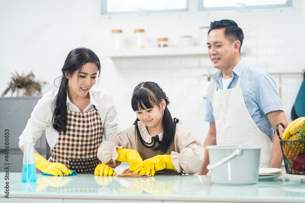 亚洲幸福家庭，父母教年幼的女儿在家打扫厨房