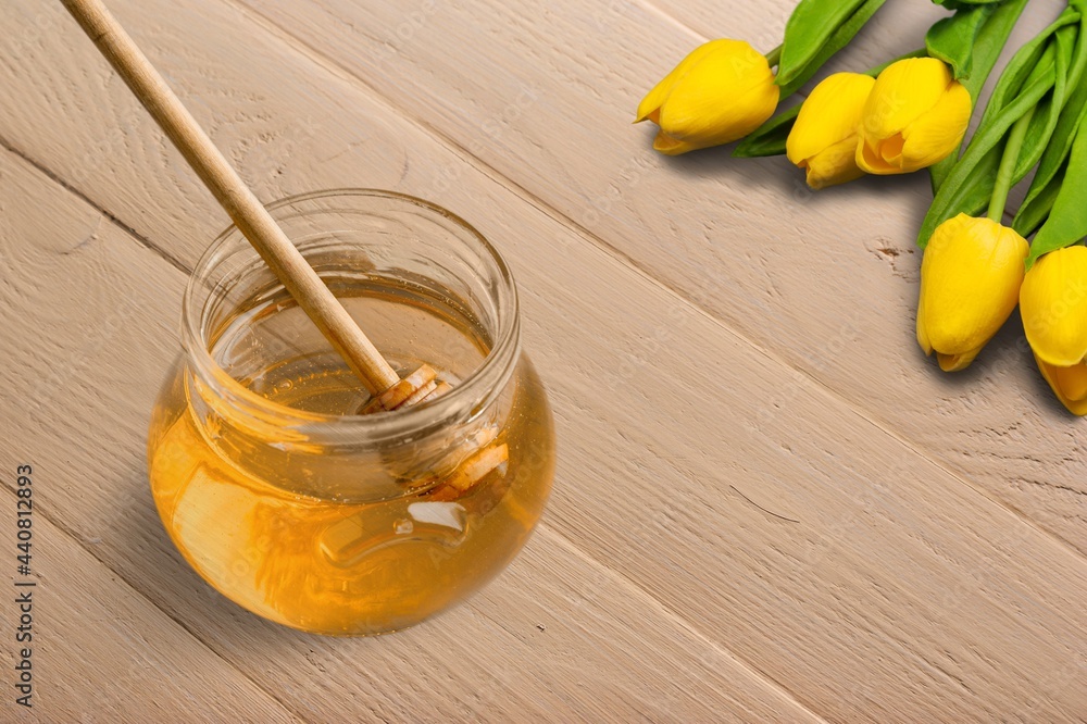 Honey dripping from honey dipper in a glass bowl.  Healthy organic Thick honey