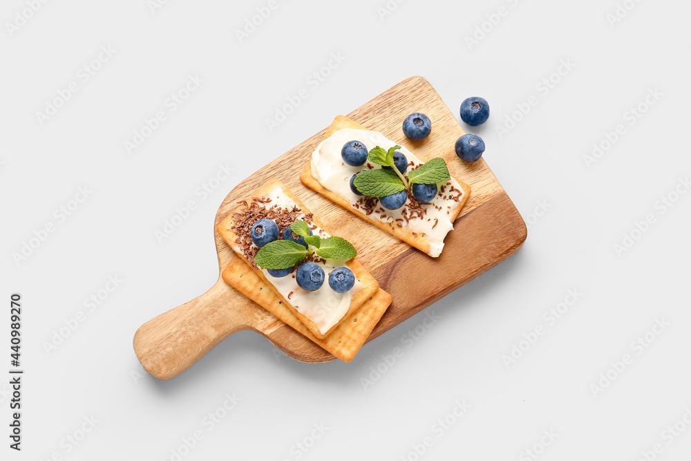 Tasty crackers with blueberry and chocolate on grey background