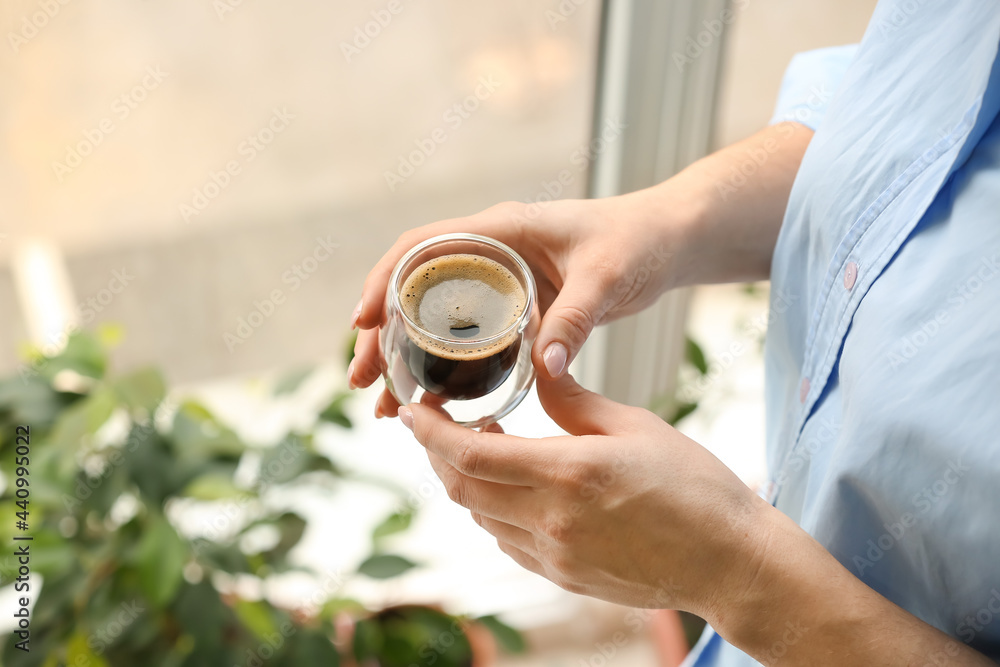 室内窗户附近的一位女士拿着一杯美味的土耳其咖啡，特写镜头