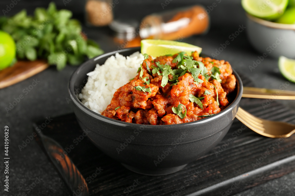 碗里有美味的辣椒肉、米饭和青柠，深色背景，特写