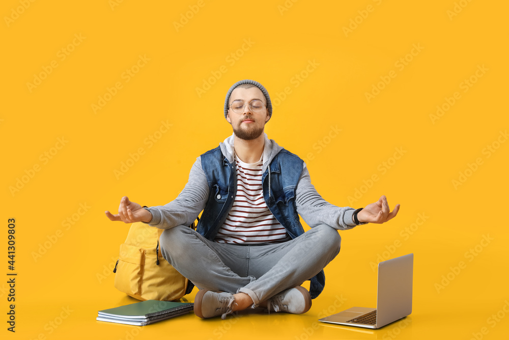 Meditating male student on color background