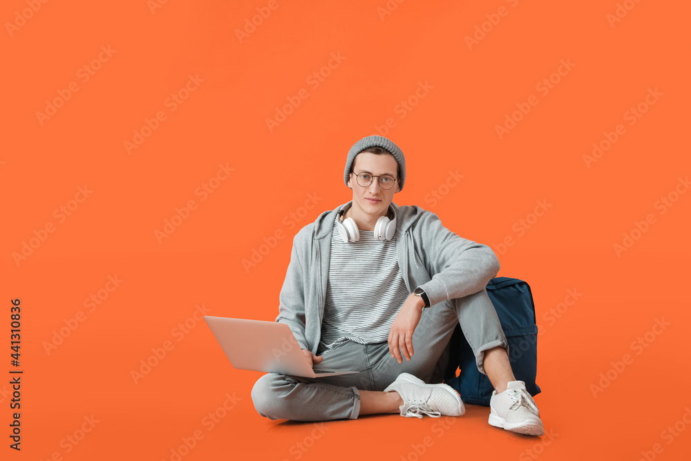 Male student with laptop on color background