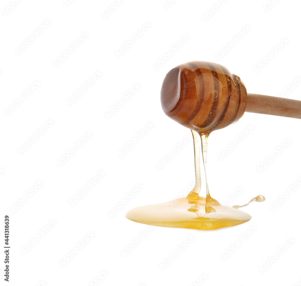 Honey pouring from wooden dipper on white background