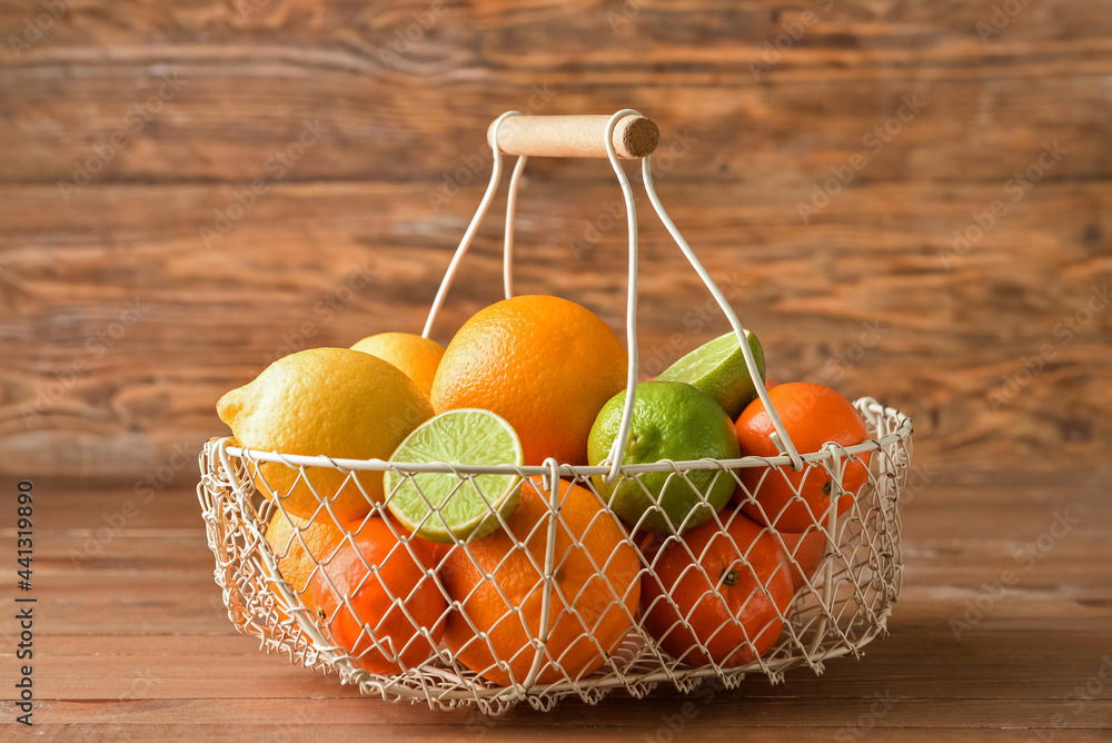 Basket with healthy citrus fruits on wooden background