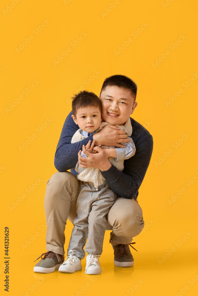 Happy father and his little son on color background