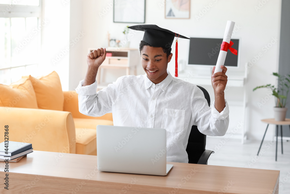 Happy African-American student on his graduation day at home. Concept of online education