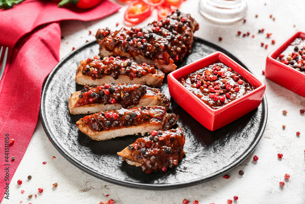 Plate with tasty roasted meat and peppercorn sauce on light background