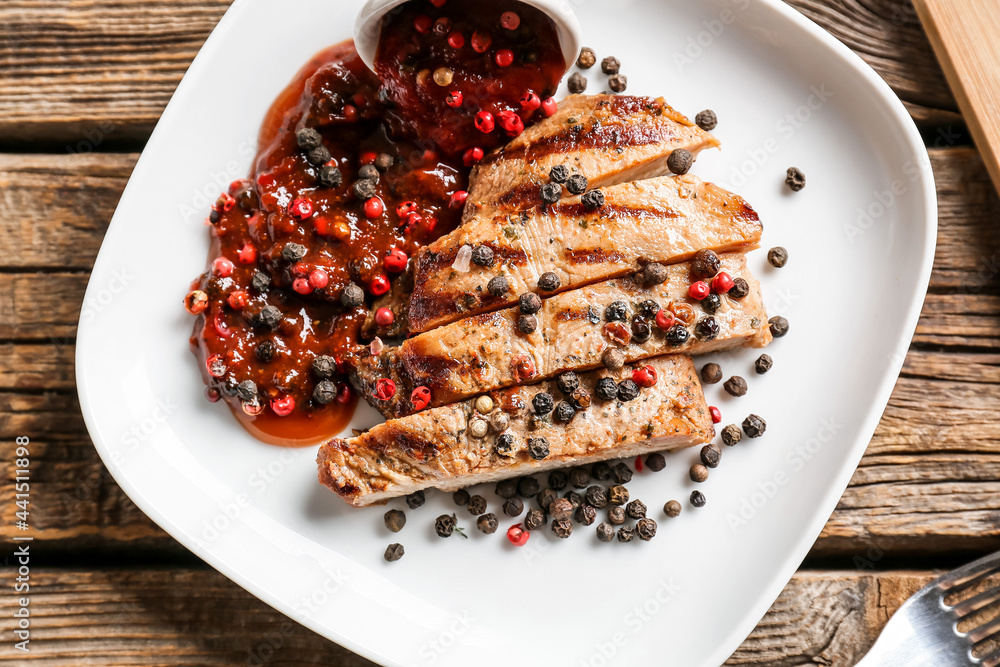 Plate with tasty roasted meat and peppercorn sauce on wooden background, closeup