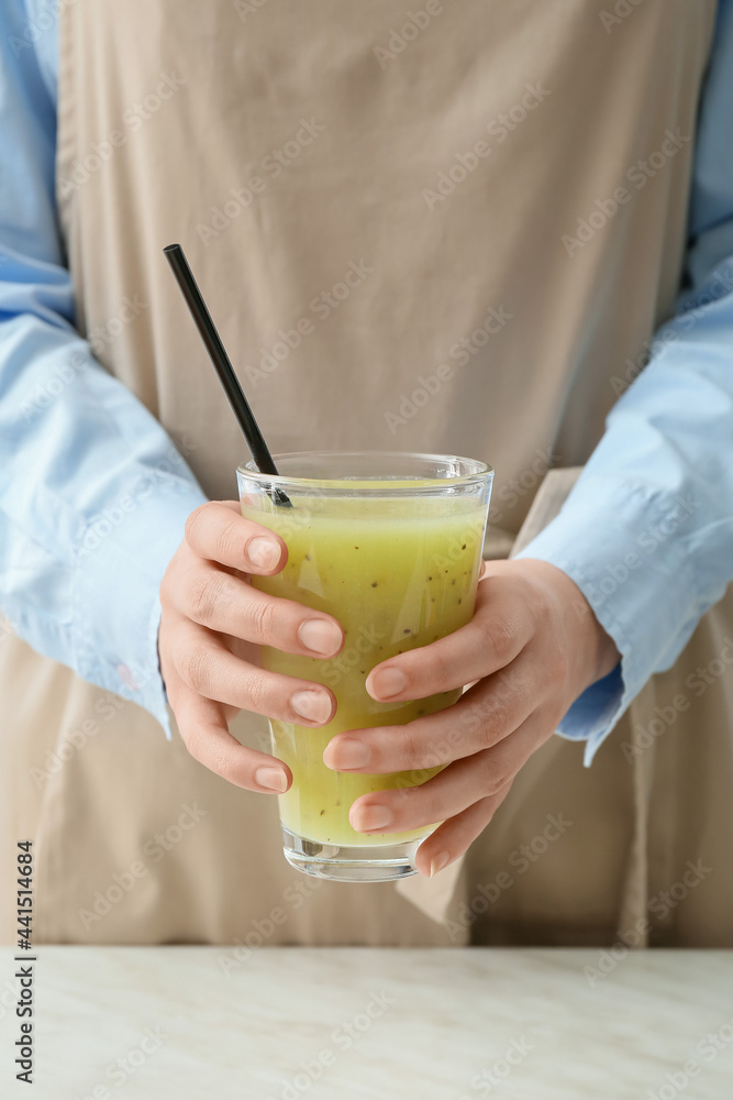 Woman with glass of healthy kiwi smoothie and ingredients, closeup