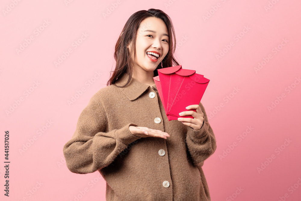 Beautiful woman holding red envelope in hand on pink background