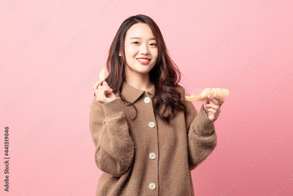 Beautiful woman making potato chips on pink background