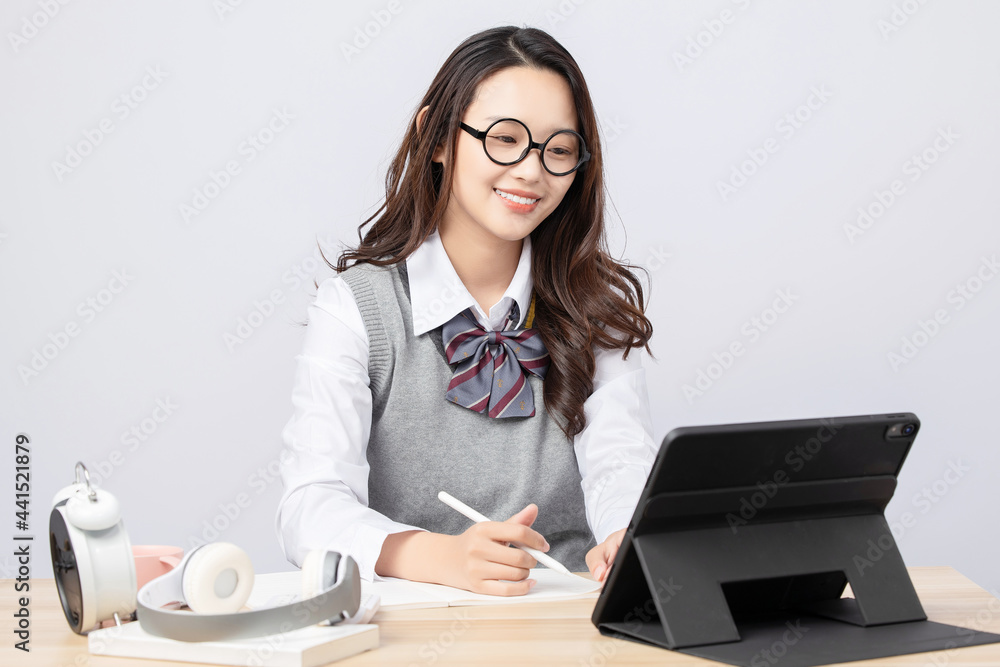 Beautiful college student girl taking online class on gray background