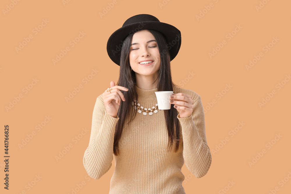 Beautiful young woman drinking coffee on color background