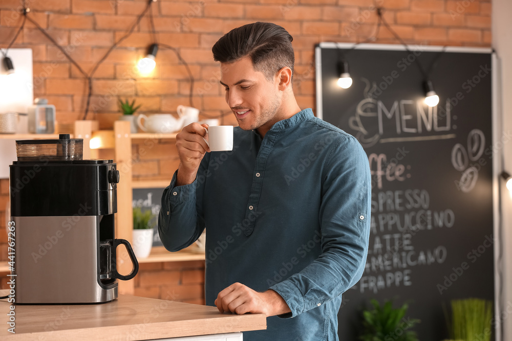 Handsome young man drinking coffee in cafe