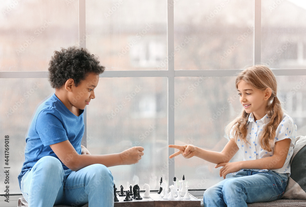 Cute children playing chess at home