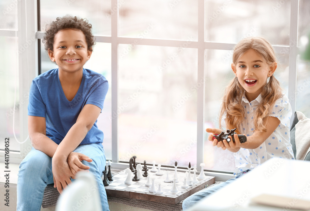 Cute children playing chess at home