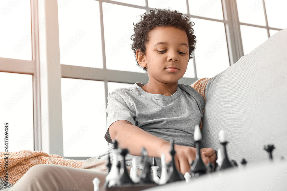 Cute African-American boy playing chess at home