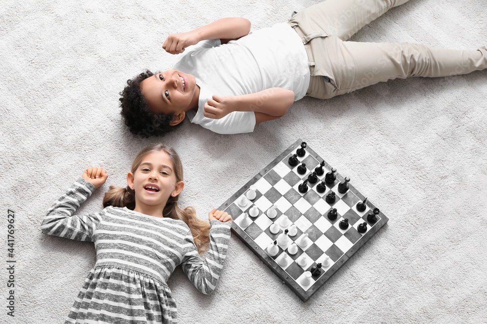 Cute children playing chess at home