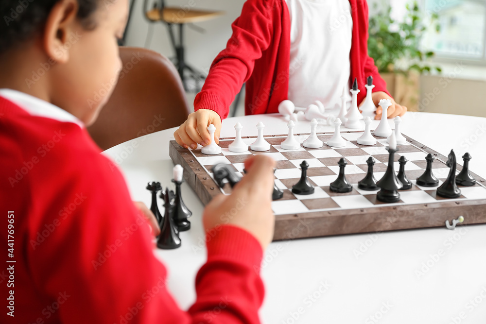 Cute children playing chess at home