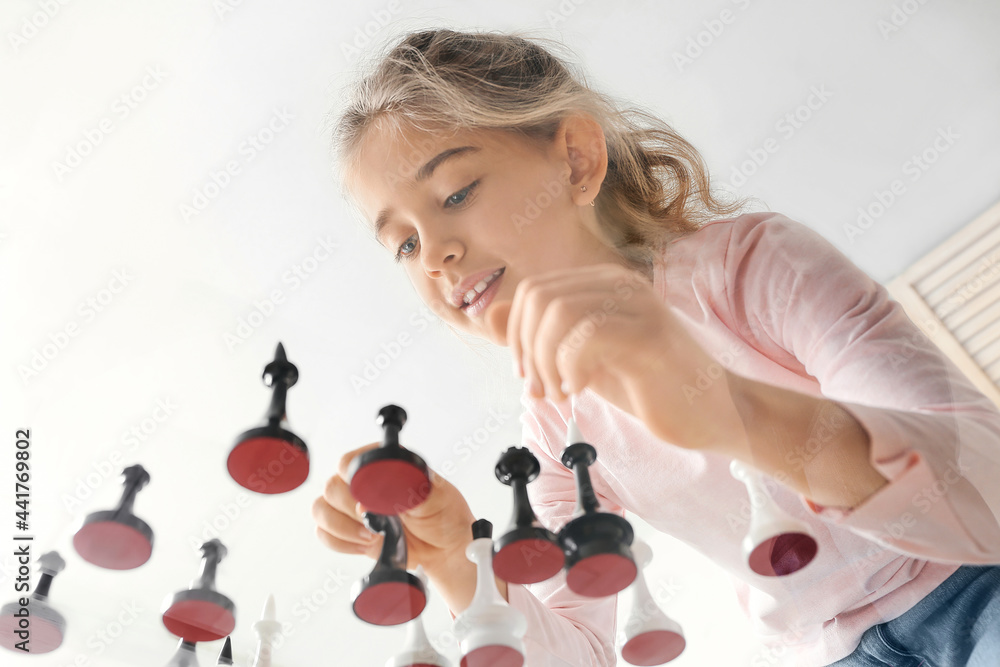 Cute little girl playing chess at home