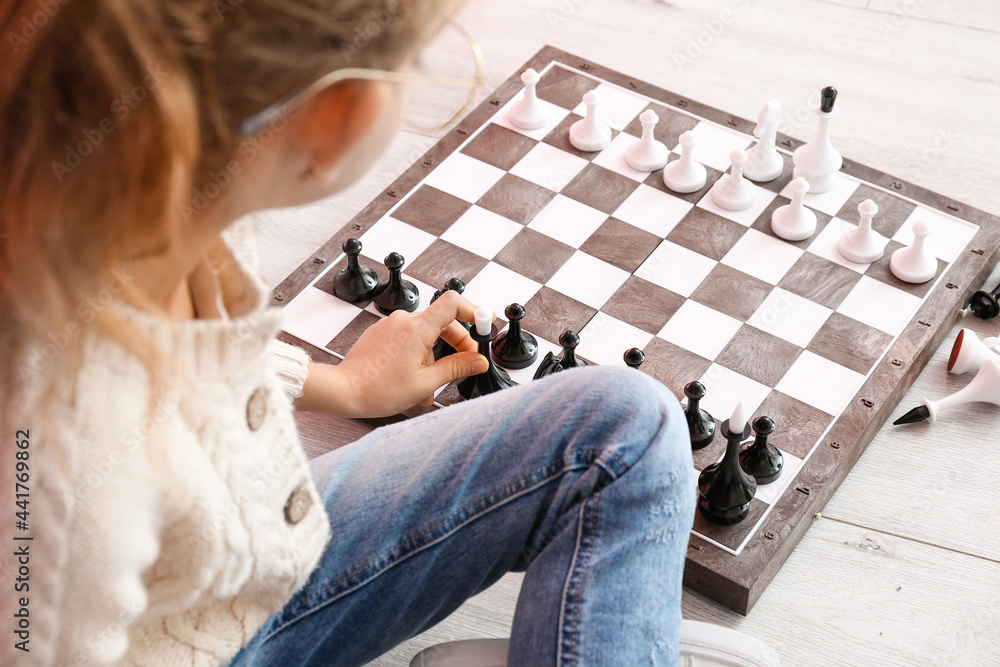 Cute little girl playing chess at home