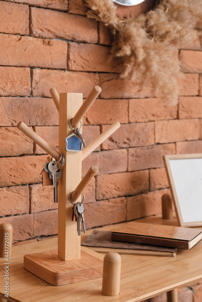 Holder with keys on table near brick wall