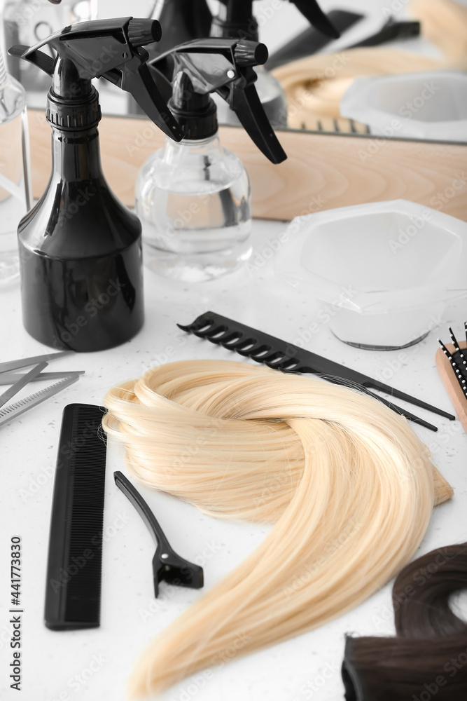 Barbers tools and strand of blonde hair on table in beauty salon