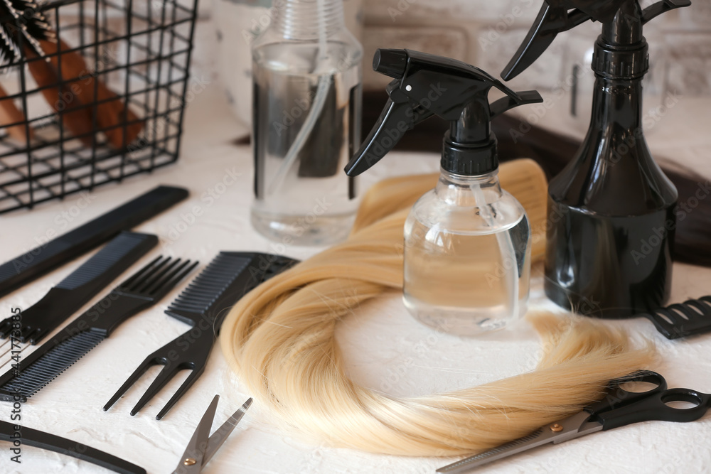 Barbers tools and strand of blonde hair on table in beauty salon