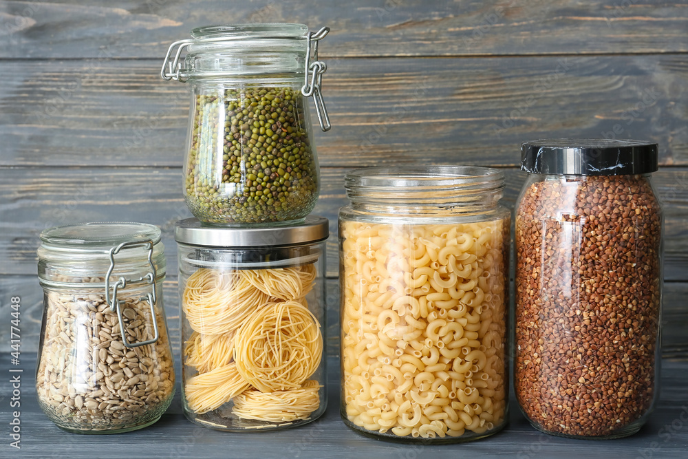 Glass jars with different products on dark wooden background