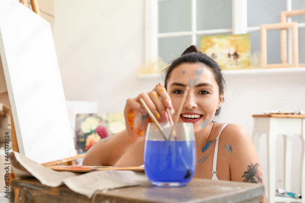 Young female artist painting in workshop