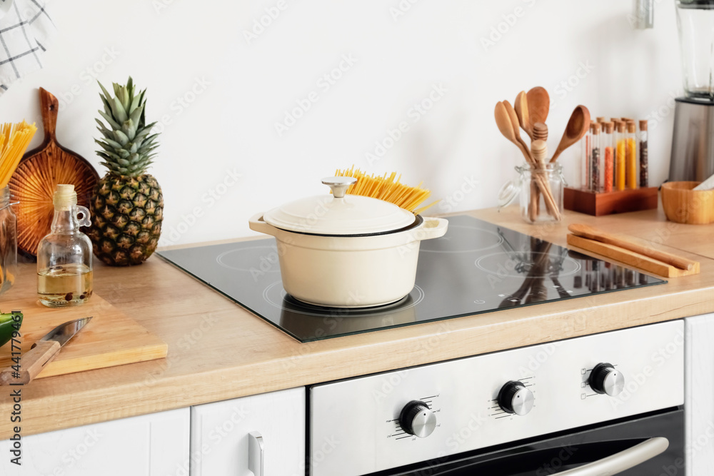 Cooking pot with pasta on stove in kitchen