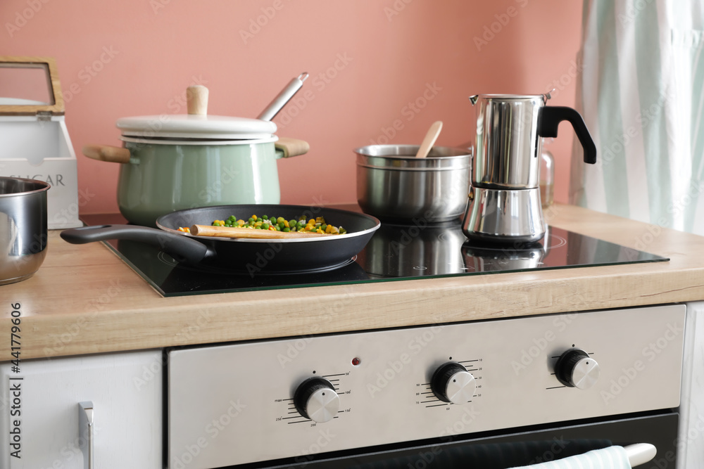 Modern electric stove and utensils in kitchen