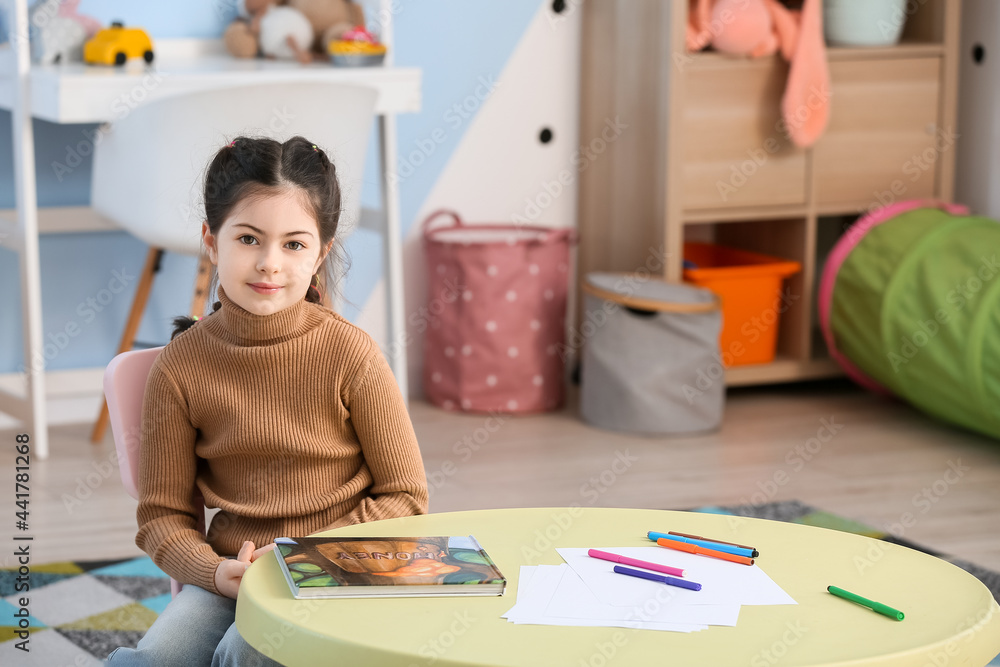 Little girl sitting at table at home