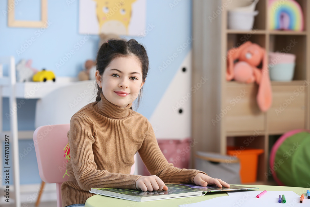 Little girl reading book at home