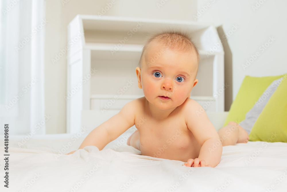 Calm beautiful baby girl standing on hands in bed