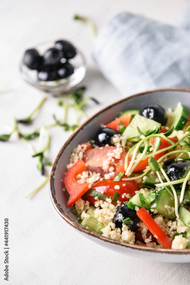 Bowl with couscous and vegetables on light background, closeup