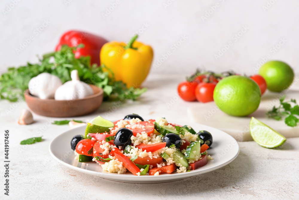 Plate with couscous and vegetables on light background