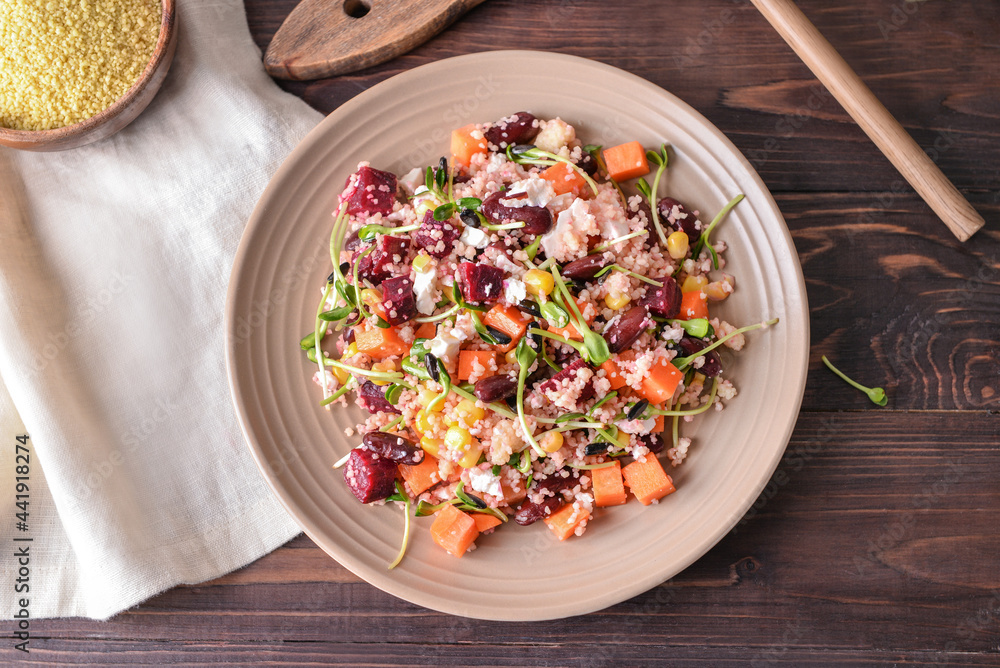 Plate with couscous and vegetables on wooden background