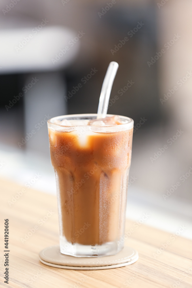 Glass of tasty ice coffee on table