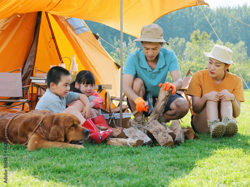 Happy family of four and dog camping out