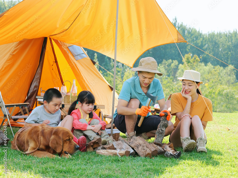 Happy family of four and dog camping out