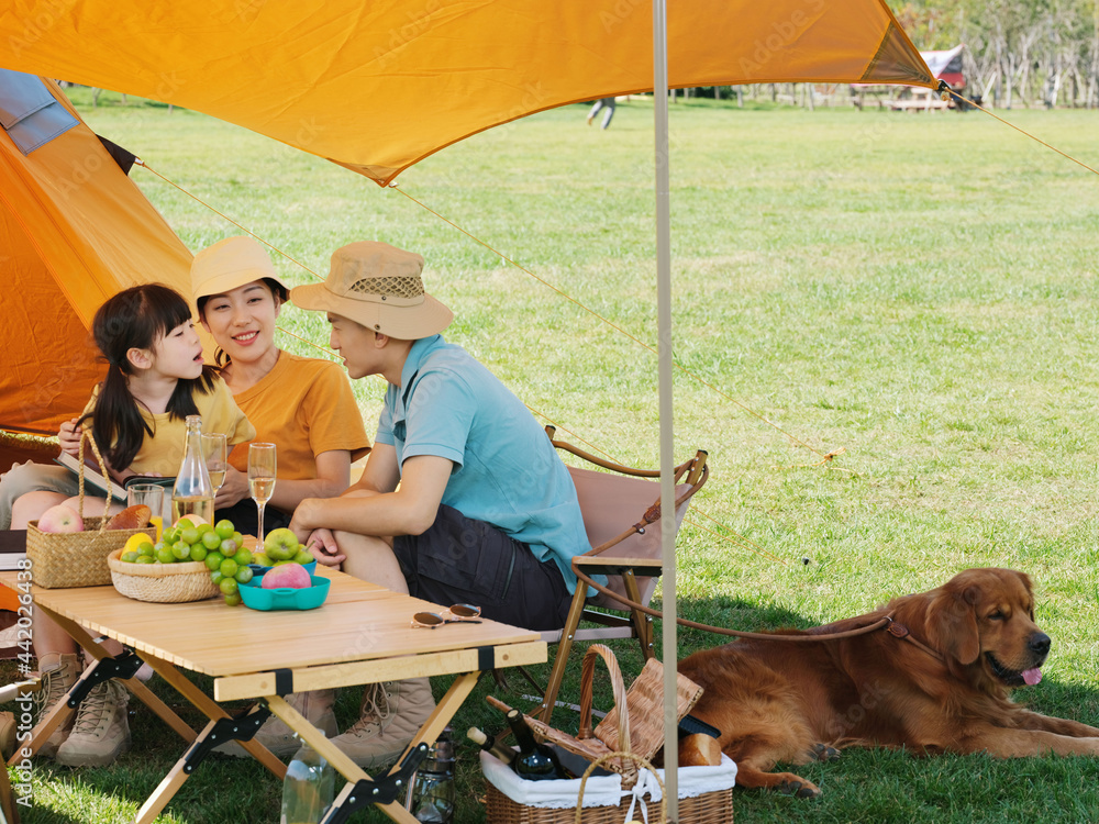 Happy family of three and pet dog reading outside